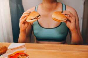 frénésie en mangeant désordre concept avec femme en mangeant vite nourriture Burger, mis à la porte poulet , beignets et desserts photo