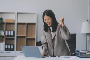 magnifique asiatique fille célébrer avec ordinateur portable, Succès content pose. commerce électronique, Université éducation, l'Internet technologie, ou Commencez petit affaires concept. moderne Bureau ou vivant pièce avec copie espace photo