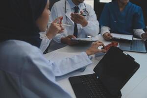 équipe de médical Personnel ayant Matin réunion dans salle de réunion. médecins et infirmières à la recherche à numérique tablette. photo