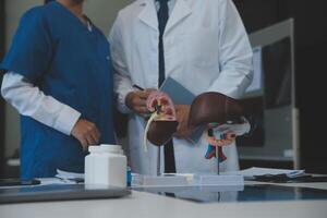 médical, réunion et portable pour équipe dans Bureau dans discussion, réflexion et planification. médecin, infirmière et ordinateur sur bureau, travail en équipe ou atelier pour modèle interne organe. photo