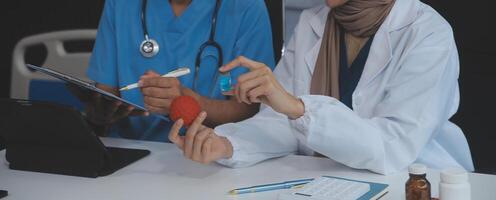 médecin discuter diagnostic pendant le réunion. groupe de médecin discuter travail matière dans le Bureau à travail. le médical équipe discute traitement les options avec le patient. photo