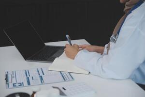 femelle médecin séance à bureau et l'écriture une ordonnance pour sa patient photo