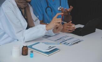 médecin discuter diagnostic pendant le réunion. groupe de médecin discuter travail matière dans le Bureau à travail. le médical équipe discute traitement les options avec le patient. photo