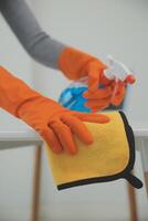 femme nettoyage table en utilisant chiffon et diffuseur à maison. photo