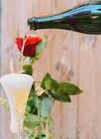 une rouge Rose accompagné par une verre de Champagne photo