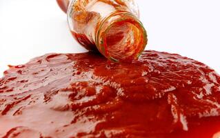 tomate sauce . verre bouteille avec ketchup. ketchup est verser en dehors de le cou de une verre bouteille. photo