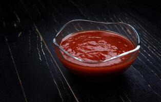 ketchup dans une verre tasse sur une noir Contexte. photo