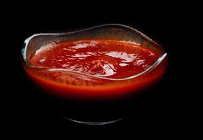 ketchup dans une verre tasse sur une noir Contexte. photo