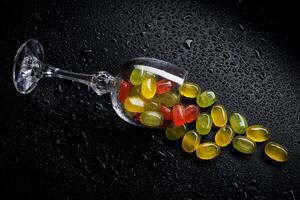 une lot de bonbons cannes sont épars de un renversé verre gobelet. multicolore des sucreries dans une verre sur une noir Contexte. confiture des sucreries. photo