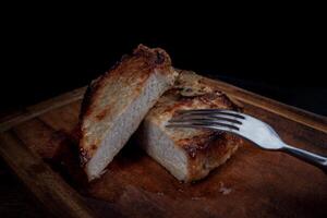 rôti porc entrecôte Couper dans pièces sur une en bois Coupe planche. fourchette dans Viande. photo