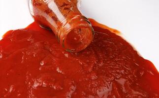 tomate sauce . verre bouteille avec ketchup. ketchup est verser en dehors de le cou de une verre bouteille. photo