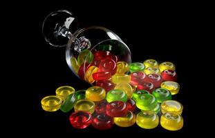 une lot de sucettes sont épars de un renversé verre gobelet. multicolore des sucreries dans une verre. photo