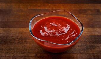 ketchup dans une verre tasse sur une en bois planche. photo