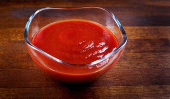 ketchup dans une verre tasse sur une en bois planche. photo