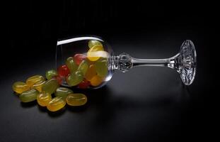 une lot de bonbons cannes sont épars de un renversé verre gobelet. multicolore des sucreries dans une verre sur une noir Contexte. confiture des sucreries. photo