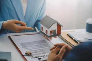 L'agent immobilier a parlé des termes du contrat d'achat de maison et a demandé au client de signer les documents pour conclure le contrat légalement, les ventes de maisons et le concept d'assurance habitation. photo