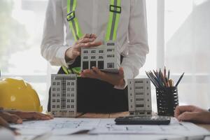 concept de construction et de structure d'une réunion d'ingénieur ou d'architecte pour un projet de travail avec des partenaires et des outils d'ingénierie sur la construction de modèles et le plan sur le chantier, contrat pour les deux sociétés. photo