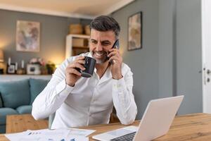 Beau homme d'affaire travail sur portable et parlant sur téléphone portable. Beau mature affaires chef séance dans une moderne Bureau photo