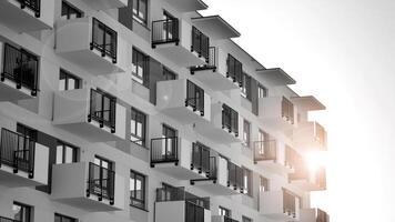 fragment de le bâtiments façade avec les fenêtres et balcons. moderne appartement bâtiments sur une ensoleillé journée. façade de une moderne Résidentiel bâtiment. noir et blanche. photo