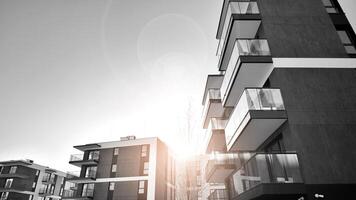 fragment de le bâtiments façade avec les fenêtres et balcons. moderne appartement bâtiments sur une ensoleillé journée. façade de une moderne Résidentiel bâtiment. noir et blanche. photo