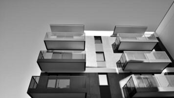 fragment de une façade de une bâtiment avec les fenêtres et balcons. moderne appartement bâtiments sur une ensoleillé journée. façade de une moderne appartement bâtiment. noir et blanche. photo