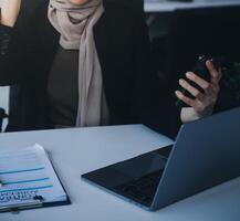 coup de un attrayant mature femme d'affaires travail sur portable dans sa poste de travail. photo