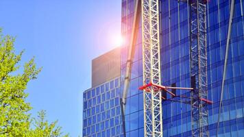 haute monter bâtiment en dessous de construction. installation de verre façade panneaux sur une renforcé béton structure. photo
