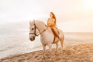 une blanc cheval et une femme dans une robe supporter sur une plage, avec le photo