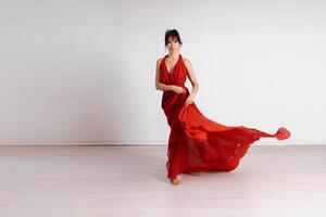 Danseur dans une rouge en volant robe. femme ballerine dansant sur une blanc studio Contexte photo