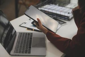 coup de une asiatique Jeune affaires femelle travail sur portable dans sa poste de travail. photo