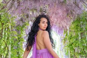 femme glycine lilas robe. réfléchi content mature femme dans violet robe entouré par chinois glycine photo