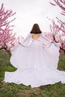 une femme dans une blanc robe est en marchant par une champ de rose fleurs. elle est en portant sa bras en haut dans le air, comme si elle est célébrer ou exprimer joie. le scène est serein et pacifique. photo