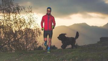 jeune coureur dans les montagnes avec chien à côté photo