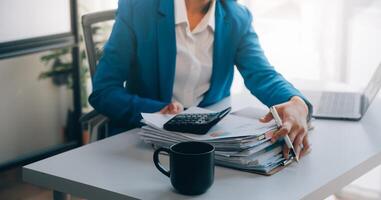 femme d'affaires joyeuse travaillant sur un ordinateur portable au bureau, belle femme d'affaires heureuse asiatique en costume formel travaille sur le lieu de travail. jolie employée de bureau souriante. photo