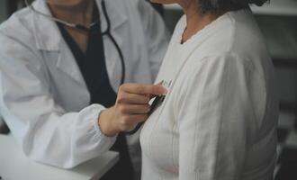 médecin en utilisant sphygmomanomètre avec stéthoscope vérification du sang pression à une patient dans le hôpital. photo