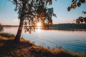 le coucher du soleil plus de tranquille lac, moulage chaud lueur plus de le l'eau et alentours paysage photo