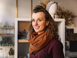 souriant femme avec frisé cheveux dans une confortable artisanat magasin réglage photo