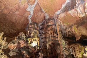 le la grotte est foncé et humide, avec mousse croissance sur le des murs. le plafond est fabriqué de rochers et le sol est couvert dans saleté. photo