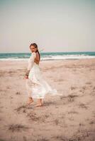 modèle dans boho style dans une blanc longue robe et argent bijoux sur le plage. sa cheveux est tressé, et là sont beaucoup bracelets sur sa bras. photo