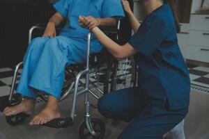 médecin donnant espoir. proche en haut coup de Jeune femelle médecin penché vers l'avant à souriant personnes âgées Dame patient en portant sa main dans palmiers. femme le concierge dans blanc manteau justificatif encourageant vieux la personne photo