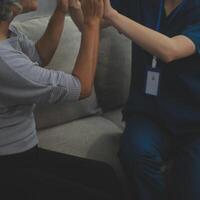 souriant gentil agréable Jeune femelle médecin dans blanc uniforme visite désactivée personnes âgées mature patient à maison, demander à propos santé état à vérification réunion, gériatrique soins de santé Aidez-moi concept. photo