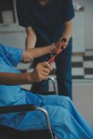 personnel entraîneur assistant Sénior femme avec la résistance groupe. réhabilitation physiothérapie ouvrier portion vieux patient à allaitement maison. vieux femme avec étendue bande étant coaché par physiothérapeute. photo