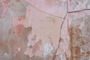 gris béton mur avec des fissures et rayures couvert avec minable rose plâtre photo