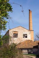 verticale image de un vieux abandonné gris papier moulin avec une brique cheminée tuyau photo