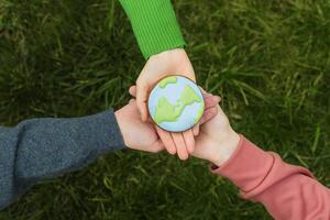 Terre journée concept. mains tenir pain d'épice dans le forme de le Terre. se soucier pour le environnement. photo