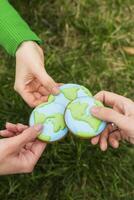 Terre journée concept. mains tenir pain d'épice dans le forme de le Terre. se soucier pour le environnement. photo