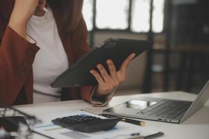 coup de une asiatique Jeune affaires femelle travail sur portable dans sa poste de travail. photo