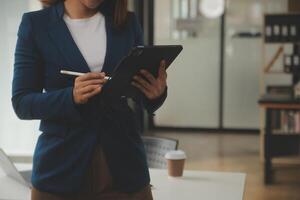 coup de une asiatique Jeune affaires femelle travail sur portable dans sa poste de travail. photo