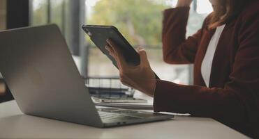 coup de une asiatique Jeune affaires femelle travail sur portable dans sa poste de travail. photo