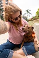 une femme avec amour regards à sa chien tandis que prise une selfie. photo